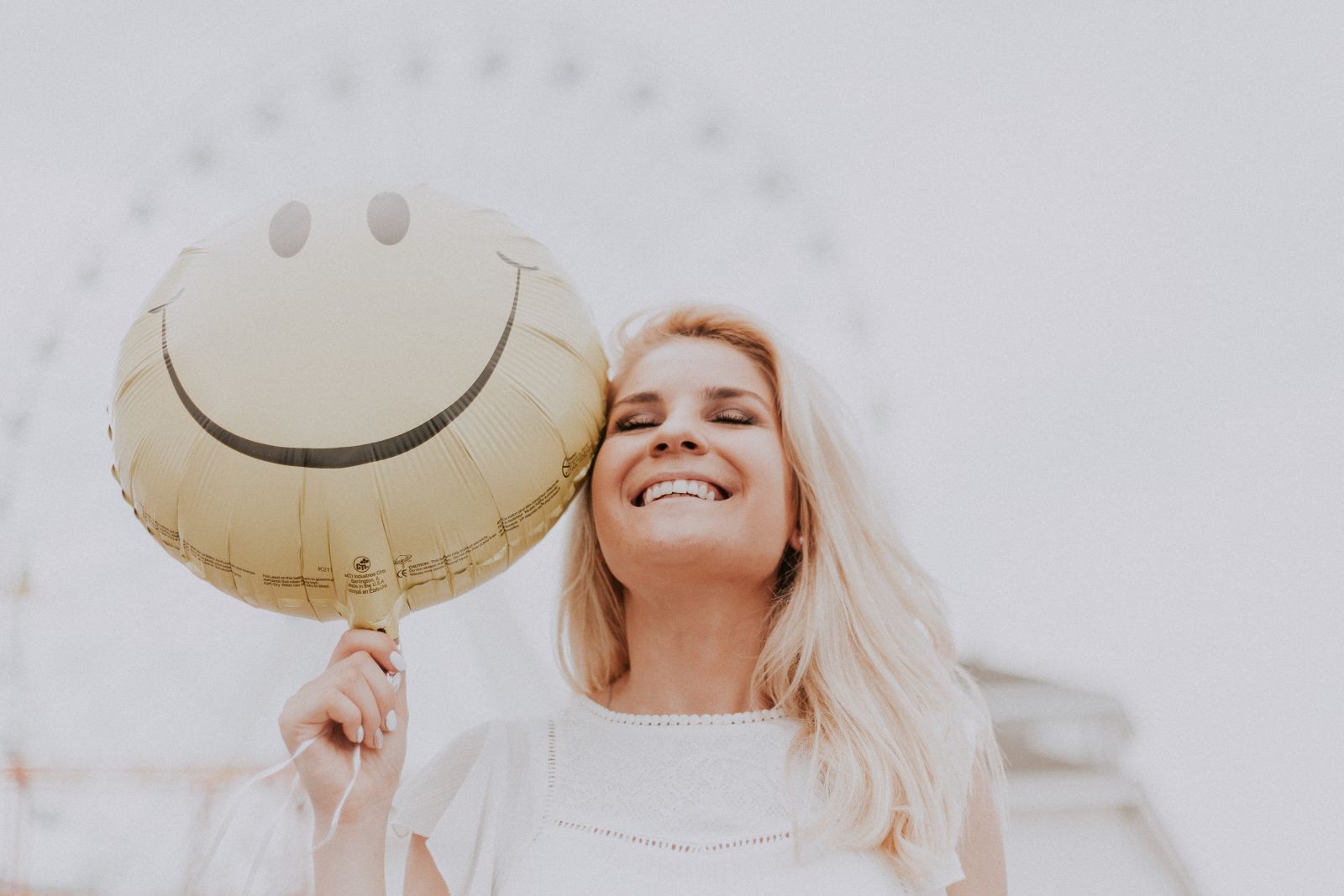 women smiling with white teeth holding yellow balloon